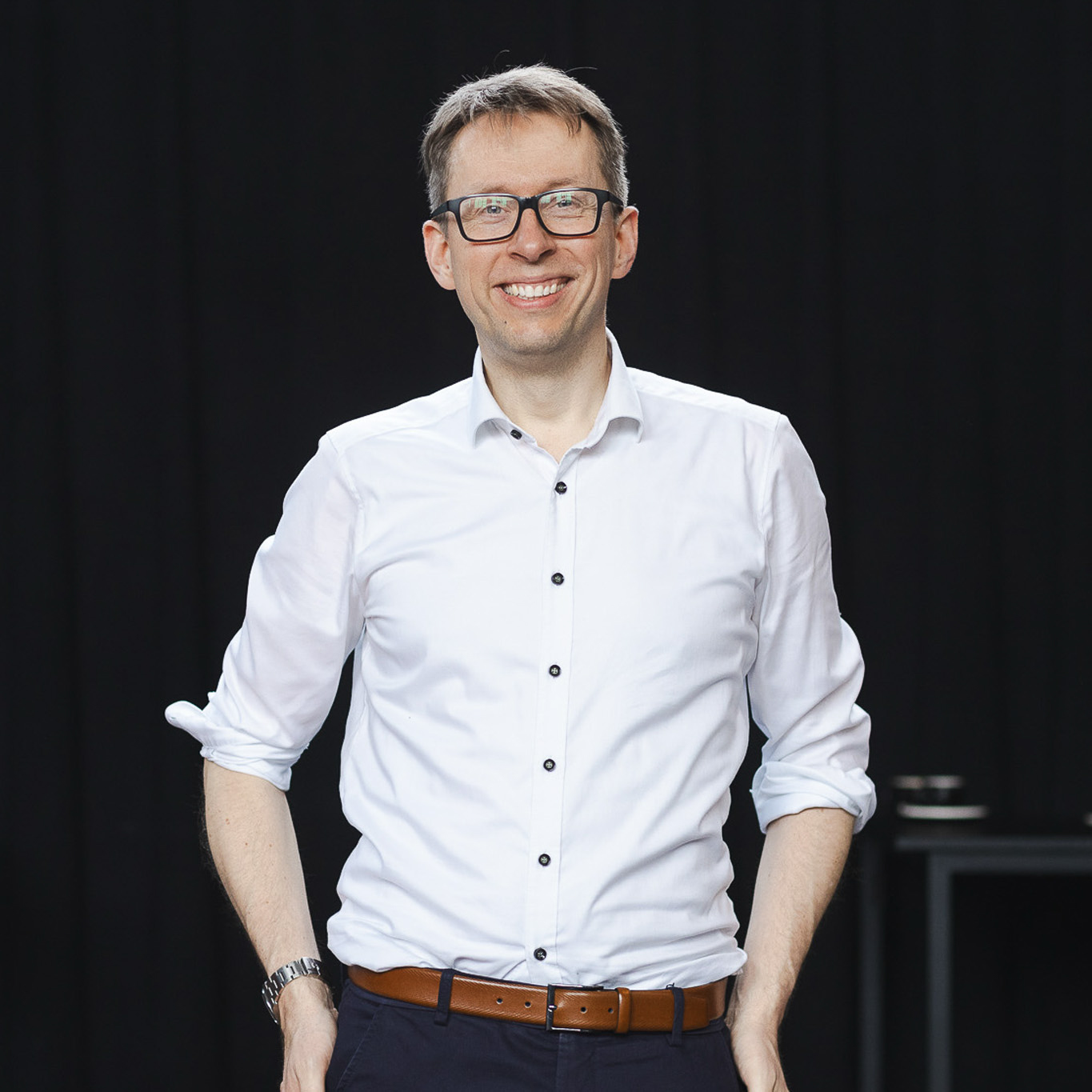 Porträt von Daniel Schwenger im weißen Hemd vor dunklem Hintergrund