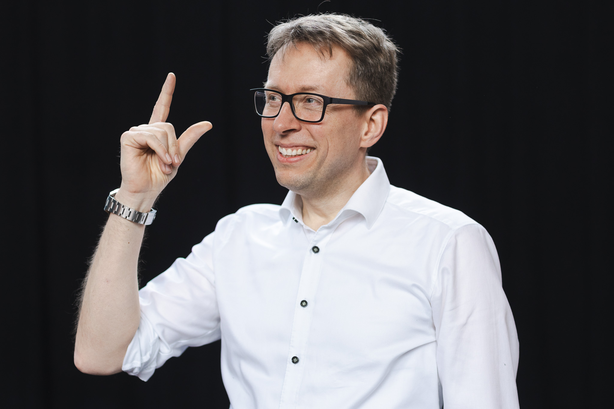 Daniel Schwenger lächelt und zeigt mit dem Finger nach oben